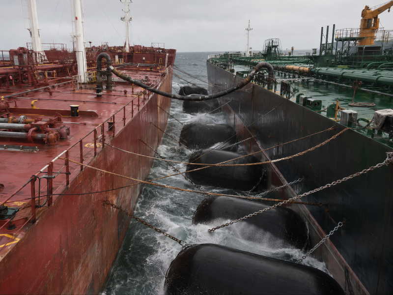 Two crude oil tankers moored alongside at anchorage with floating pneumatic fenders compressed between the hulls