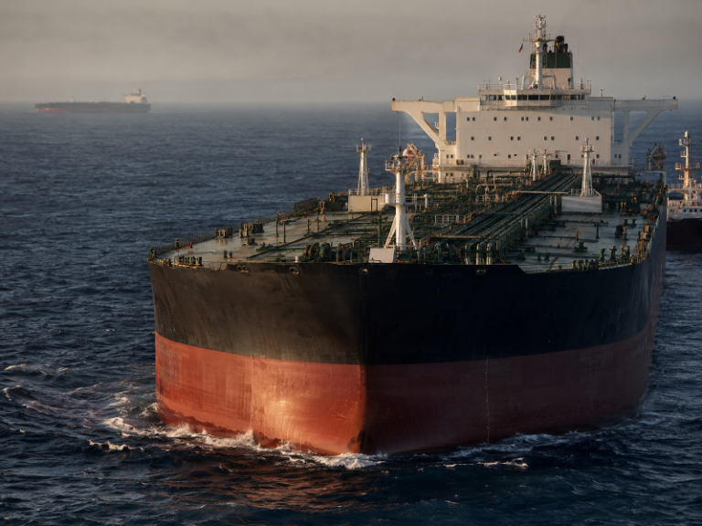 Loaded crude oil tanker under way in open water, seen from the bow quarter at first light